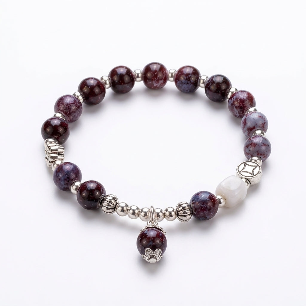 A beaded stretch bracelet featuring dark purple and marbled gray beads, silver-toned spacer beads, a white stone accent, and a small dangling silver charm, displayed on a clean white background.
