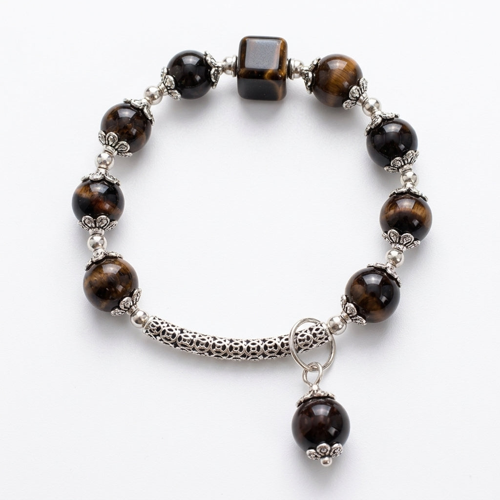 A beaded stretch bracelet featuring tiger's eye beads in brown and black, silver-toned spacer beads, a textured silver tube, and a dangling round bead charm, displayed on a clean white background.