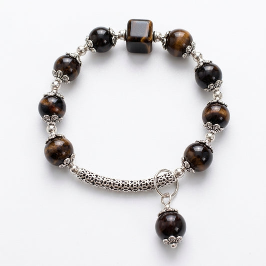A beaded stretch bracelet featuring tiger's eye beads in brown and black, silver-toned spacer beads, a textured silver tube, and a dangling round bead charm, displayed on a clean white background.
