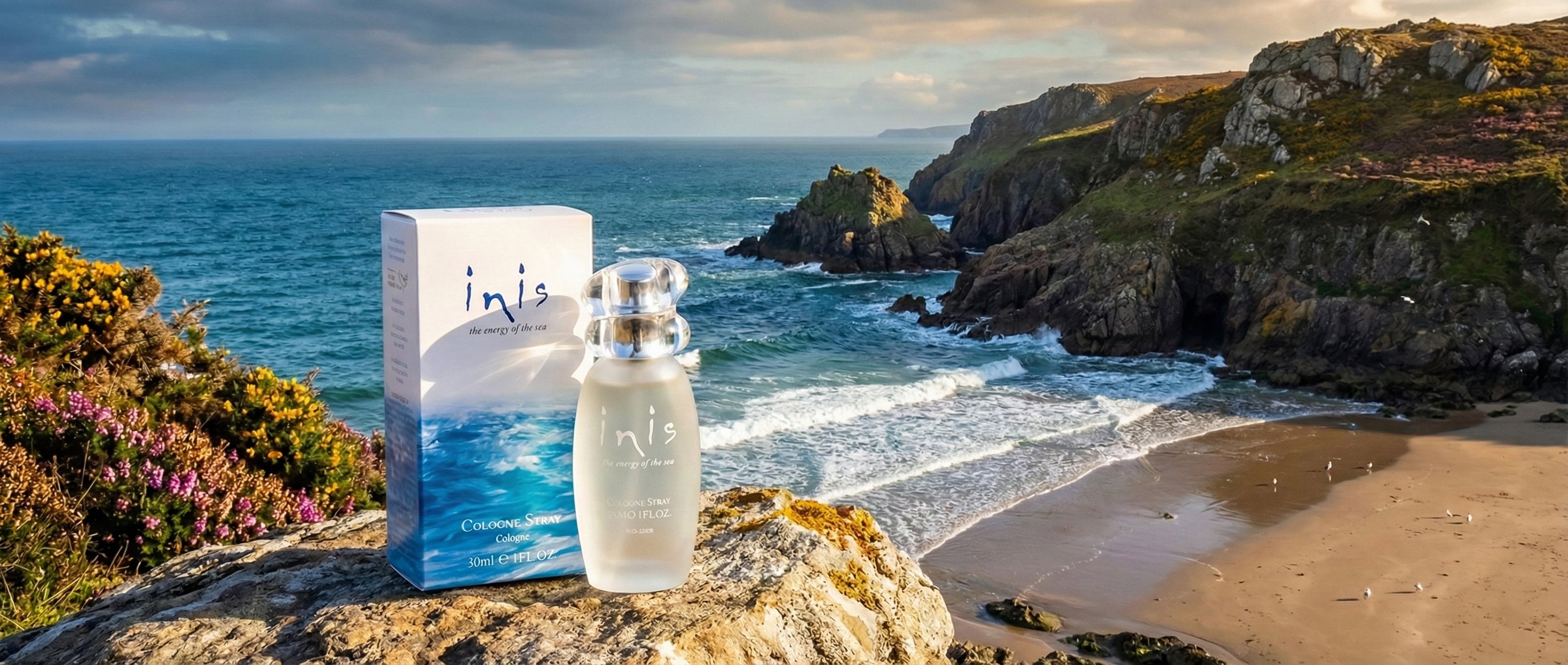 Inis perfume bottle and packaging on a rocky beach with ocean and cliffs in the background